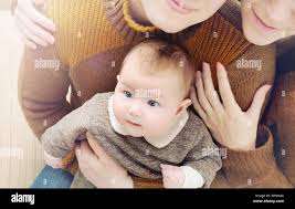Happy Family Of Three Little Cute Baby With Big Eyes Sitting On The Parent S Knees Family Concept Stock Photo Alamy