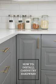 The kitchen cabinet doors in timber provide a soothing contrast to the pristine white cabinets below, which almost merge with the white walls around. How To Choose And Install Gold Hardware Pulls In Your Kitchen The Sweetest Digs