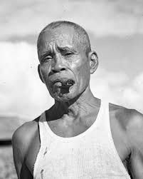 Photograph of a man leaning against palm in Yasawa Islands, Fiji, circa  1960s, by Harrison Forman, 1904-1978.