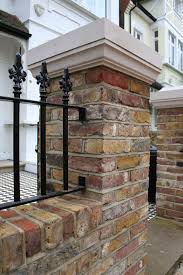 The design features liberal use of stones and bricks for the walls. Brick Pillar And Black Railings In Contemporary London Front Garden A Narrow Bed Enclosed With Concrete St Brick Pillars Front Garden Front Garden Design