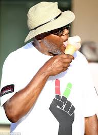Samuel L Jackson eats ice cream as he walks with Magic Johnson