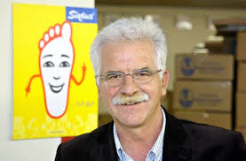 Anton Becker vor einer Spiegelvitrine mit Produkten des