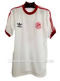 La camiseta local hace uso del template con cuello cerrado que le vimos a equipos como santos y cruzeiro, adoptando base blanca con una banda cruzada blanca sobre el frente. Camiseta Argentinos Juniors F Redondo