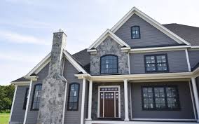 Modern craftsman dark blue wood shakes with vertical trim siding and natural stone home showcases charcoal country squire exterior stone veneer masonry with light blue trim, pillars, and black shutters. House Facade And Full Chimney With Sterling Gray In Mosaic