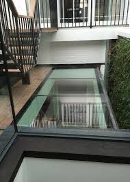 Vertical concrete stairs with side walls and handrails under sloping slant glass roof. Glass Roofs Glasstec Systems