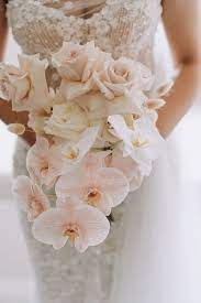 Classy floral arrangement in a pastel round bouquet featuring pink hydrangea roses and orchids, set on an elegant glass support as a centerpiece for a wedding reception ceremony or as formal decor. Wedding Bouquets With Orchids Arabia Weddings