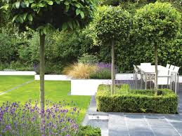 An Outdoor Dining Area Is Defined By Clipped Lollipop Bay Trees That Emerge From Box Framed Lavender Beds Garden Retaining Wall Garden Structures Garden Design