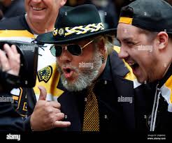 Boston Bruins fan Larry Westgate, left, poses for a television camera with  others outside the arena before Game 2 of the NHL hockey Stanley Cup Final  between the Bruins and the St.