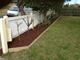 Surrounding the walkway is a bed of bark with plants and rocks interspersed to create a cohesive garden design. 7 Ideas For Garden Edging Landscape Timber Edging Wooden Garden Edging Landscape Timbers