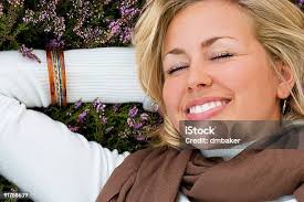 Beautiful Blond Woman Laying Down Smiling In Purple Heather Stock Photo