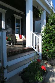 The facade of a black house doesn't always need to be all black. Front Porch On A Dark Weathered Blue House White Trim Black Shutters With Pops Of Red As Highlights Outdoor Living Space Outdoor Living Blue House