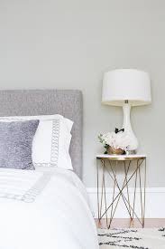 Simple And Cozy This Bedroom Features A Round Marble And Brass Bedside Table With A Milk Glass G Bedside Table Brass Marble Bedside Tables Bedside Table Decor