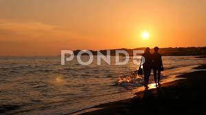Romantic couple holding hands watching the sunset on the beach. Summer Romantic Sunset Couple Walk On T Stock Video Pond5