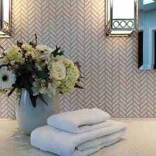 White kitchen cabinets are mounted over marble ogee tiles and beside a window positioned above white cabinets contrasted with a dark gray quartz countertop. Gray Corian Countertops Design Ideas