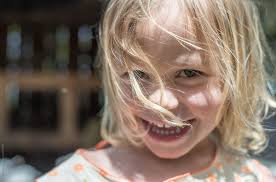 Happy Little Girl With Hair Blowing In Her Face" by Stocksy Contributor "Cara  Dolan"