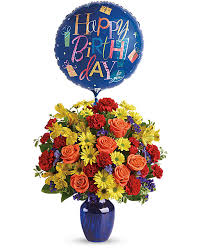 Bunch of colorful flowers, flower bouquet with text happy birthday bunch of roses and gift box with an empty tag on wooden background pink flowers in the basket next to card with phrase: Fly Away Birthday Bouquet Teleflora