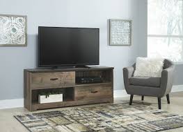 This low profile, classic long tv bench is featured in our rich espresso wood grain finish accented with imitation nickel handles, includes 2 drawers and 2 open center shelves and two cupboards. The Trinell Brown Large Tv Stand Available At Furniture City Serving Jackson Yazoo City And Vicksburg Ms