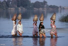 women raising their dress to cross a river carrying jars on the head in egypt egypt culture egyptian beauty life in egypt
