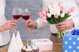 Free Photo Couple Clinking Wine Glasses With Tulip Flowers Bouquet Birthday Cake And Gift Boxes On Table