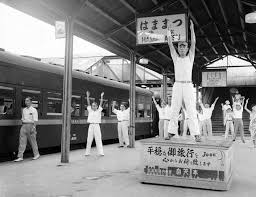 月台上有人示範健身操 讓乘搭長途車的乘客學會做此健身操以避免身體過度疲勞 1952年8月27日 japan history japan osaka