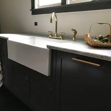 Maybe you would like to learn more about one of these? The Dark Cupboards And White Farmhouse Sink Are Highlighted By Brass Accents And Faucet In This Modern Kitc White Farmhouse Sink Farmhouse Sink White Farmhouse