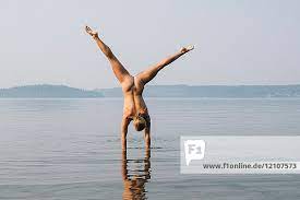 Rear view of nude couple in water jumping in mid air
