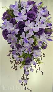 This natural touch and silk bouquet features silk purple rosebuds, silk purple/gold hydrangeas, natural touch natural white rosebuds and open roses accented by a cream satin partial stem wrap with a purple pearl seam. Silk Wedding Bouquet Artificial Flower Purple Lilac Rose Orchid Teardrop Flowers Wedding Table Flowers Wedding Bouquets Silk Flowers Wedding