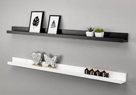 This twist on the traditional photo ledge features a top ledge with a lip to keep the frame from tipping out and falling off the shelf, which also gives it a modern cohesive art display style. Wooden Picture Shelves Austin Hart