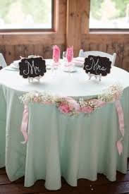 A rustic dining set with a fabric and a greenery runner and pink glasses for a bridal shower. 80 Best Bridal Shower Table Decoration Ideas Bridal Shower Bridal Shower Table Decorations Bridal Shower Tables