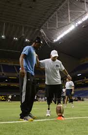 U.S. Army Reserve Spc. Justin Lane (right) prepares to punt a football with  help from high school football player Kameron Miles at the Alamodome in San  Antonio Jan. 2, 2013. Miles, a