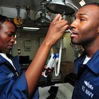 Seaman Nickolas Davidson, left, and Personnel Specialist 2nd Class Jesus  Salazar conduct a body composition assessment (BCA) aboard the  guided-missile destroyer USS Stout (DDG 55).