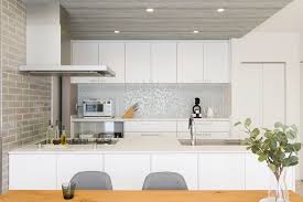 キッチンはあえて天井を少し下げ グレーの木目調に ダイニングとのメリハリを生み デザイン性を高めている 壁のタイルは 同じグレーでも色味や素材感の違う種類を組み合わせることで より洗練された空間に仕上げた リビング 木目 リビング キッチン キッチン