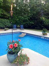 Pool deck, composite, composite rail. Tiki Torches In The Flowers Around The Pool Landscaping Around Pool Inground Pool Landscaping Backyard Pool Landscaping