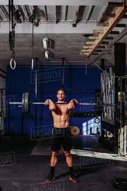 Athletic male with naked torso doing deadlift with heavy barbell while  pumping muscles in sports center - Stock Photo - Dissolve