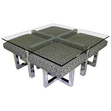 A pretty modern coffee table with 4 nesting stools having rectilinear grey frames of wooden materials. 1960s Milo Baughman Style Glass Top Coffee Table With Nesting Ottomans For Sale At 1stdibs
