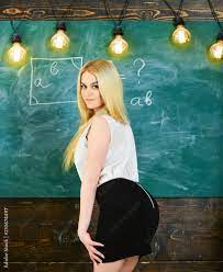 Lady sexy teacher in short skirt looking back while explaining formula. Sexy  teacher concept. Woman with nice buttocks teaching mathematics. Teacher of  mathematics writing on chalkboard, rear view. Photos 