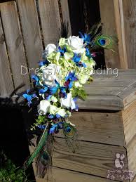 This teardrop bouquet of dyed blue singapore and white orchids would be appropriate for a beach wedding or a formal wedding. Dress My Wedding Purple Blue Orchid Bouquet Hydrangeas Roses Peacock Feather Bouquet Dendrobium Orchids