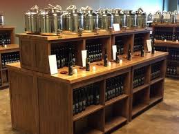 Double Sided Fusti Bar Riser Table Display Rustic Wood Olive Oil Vinegar Open Shelves Gourmet Retail Store Woo Olive Oil Store Store Displays Retail Fixtures
