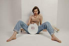 Confident young woman sitting with spread legs and showing banner with Grl  Pwr inscription · Free Stock Photo