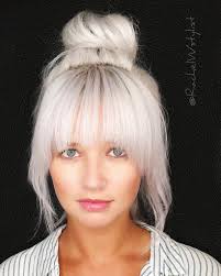 Large Messy Top Bun With Full Face Framing Fringe And Platinum Blonde Hair Color Platinum Blonde Hair Blonde Hair With Bangs Platinum Blonde Hair Color