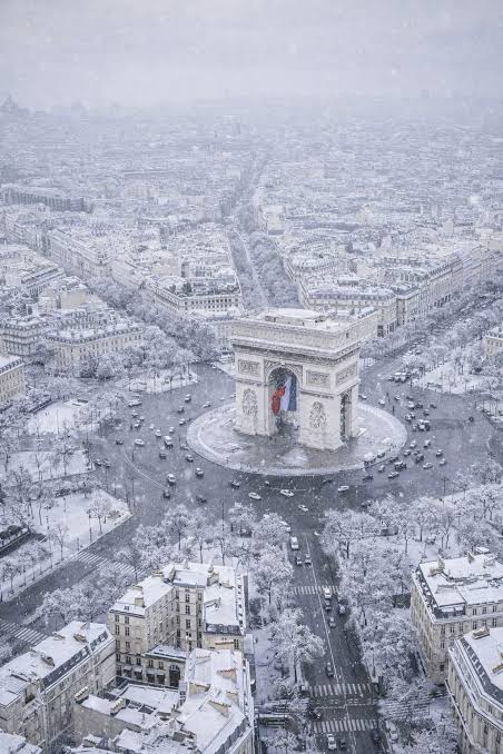 Aerial view of the Arc de Triomphe in Paris, France, covered in snow.