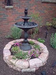 With decorative eyes, nose and mouth in the garden of a house with parked car visible behind decorative tree stump. 17 Tree Stomp Cover Ideas Garden Design Tree Stump Tree Stump Planter