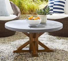 This cement outdoor coffee table features a neutral color scheme and natural material finish that make it a good match for wicker outdoor furniture. Abbott Indoor Outdoor Concrete Fsc Acacia Round Coffee Table Brown Pottery Barn