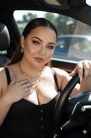 A rich, confident Black woman rides a jet ski across the ocean with the  Miami skyline in the background. She wears a luxury monogram bikini and a  matching designer headscarf tied around
