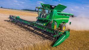 Combine and tractor trailer harvest wheat. History Of Combine Harvester A Brief Timeline From 75 A D