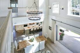 Two Story Dining Room Features Tiered Iron Candelabra Chandelier Illuminating A Reclaimed Wood Dining Table Lined Wit Home Family Room Transitional Dining Room
