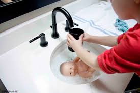 Child playing with water and soap bubbles in sunny kitchen with window. Baby Doll Bath A Quick And Easy Toddler Activity Busy Toddler