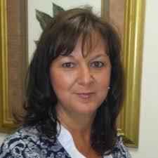 A zebra-crossing leading to a road divider with shrubs and trees before a… 