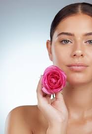 Soins de la peau du visage et femme avec fleur rose en studio isolé sur fond
