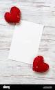 Blank sheet of paper and red love hearts on wooden table ...